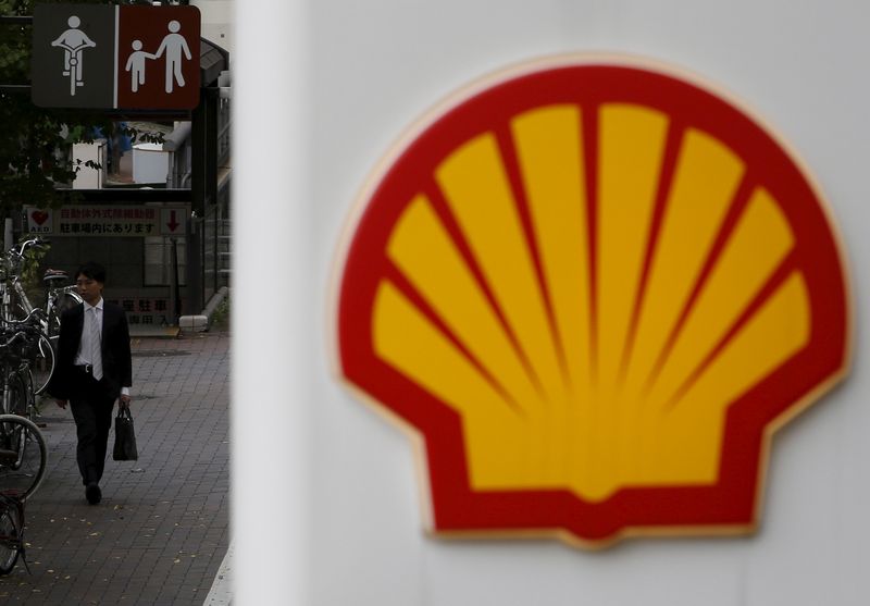 A man walks behind a signboard of Showa Shell Sekiyu at its gas station in Tokyo November 11, 2015. u00e2u20acu201d Reuters pic