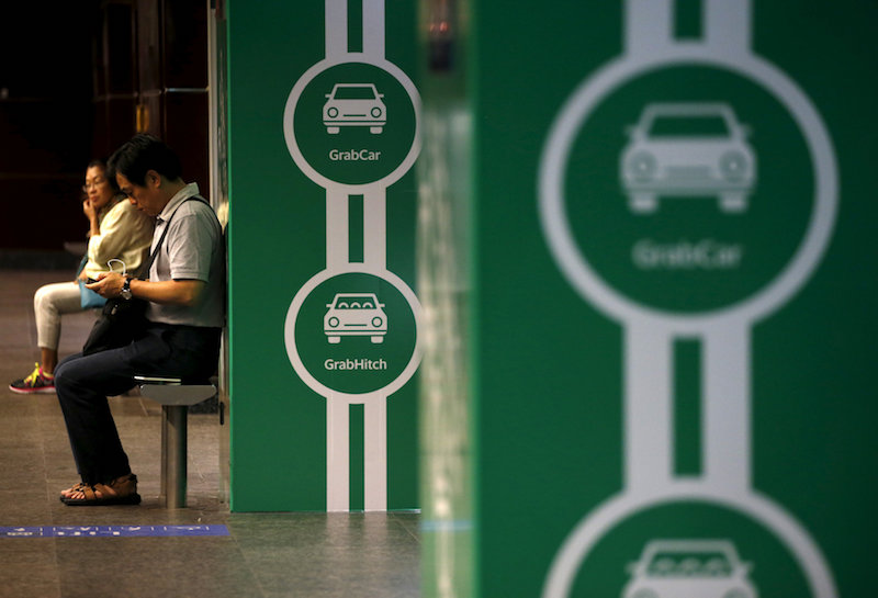 Commuters wait for a train next to Grab transport booking service app advertisements at a train station in Singapore February 10, 2016. u00e2u20acu201d Reuters pic