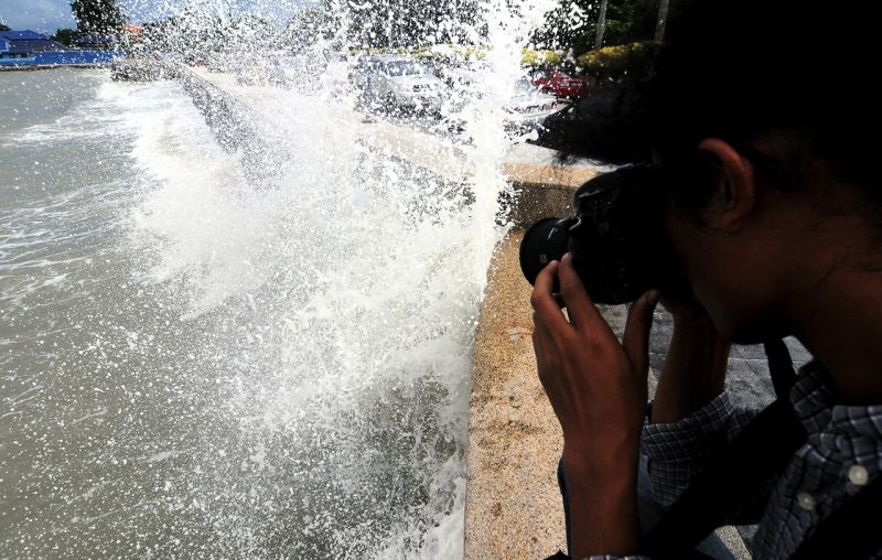 A man takes pictures of giant waves hitting the barrier at the Esplanade beach in Penang September 22, 2016. u00e2u20acu2022 Bernama pic