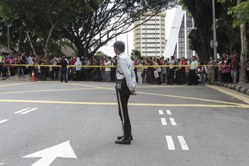 A traffic police officer watches as the Bursa Malaysia building's occupants behind police cordon are informed that they can re-enter the building. ― Picture by Yusof Mat Isa