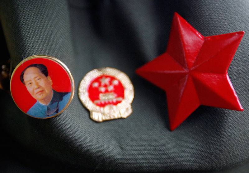 A badge bearing the portrait of former Chinese Chairman Mao Zedong can be seen attached to a hat next to a Chinese Communist Party badge and a red star at a market in Beijing July 1, 2008. u00e2u20acu201d Reuters picn