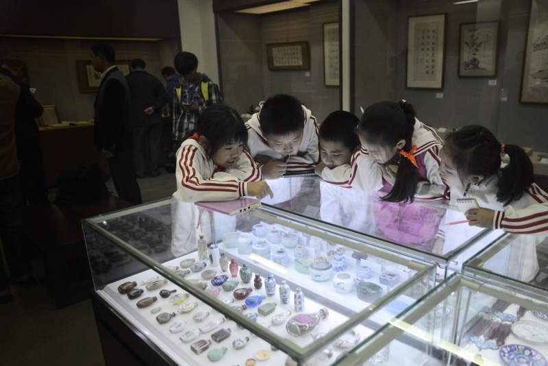 This picture taken on October 24, 2016 shows schoolchildren looking at a collection of antiques from Jin Yulan, the nephew of China’s last emperor Pu Yi, in Beijing. — AFP pic