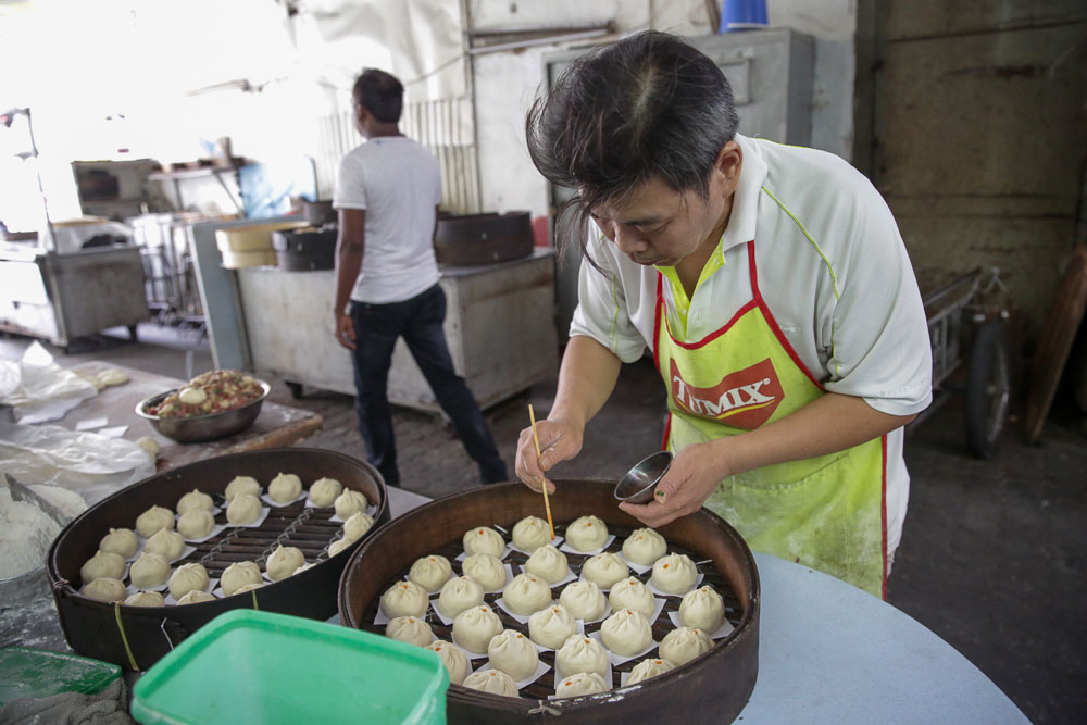Chan Kam Weng preparing his pau (steamed bun) for customers. He makes about 300 pau in one day, all handmade to perfection.