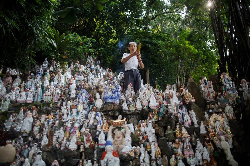 Wong Wing-pong, an 85-year-old retired butcher, offers incense to unwanted statues of deities, gathered and repaired after their owners discarded them, on a rocky slope running down to the sea in Hong Kong August 9, 2016. u00e2u20acu201d AFP pic