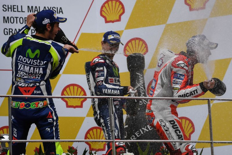 Second-placed Movistar Yamahau00e2u20acu2122s Valentino Rossi (L) and third-placed Movistar Yamahau00e2u20acu2122s Jorge Lorenzo (C) spray champagne at Ducati Teamu00e2u20acu2122s race winner Andrea Dovizioso (R) Sepang International circuit October 30, 2016. MOHD RASFAN / AFP