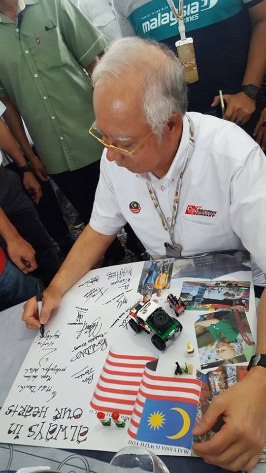 Prime Minister Najib Razak signs a card to help raise awareness and pull Malaysians together to donate to Muhammad Danish Maarif’s family.