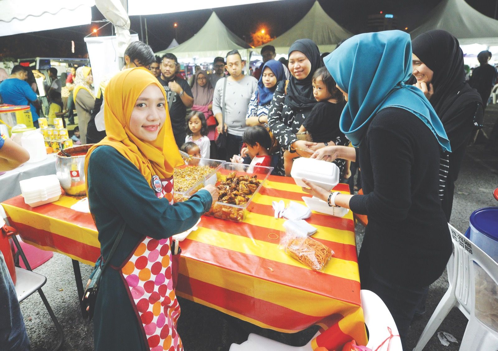 Siti Hajjar serves a customer while a long line of people wait their turn. u00e2u20acu201d Picture by Mukhriz Hazim