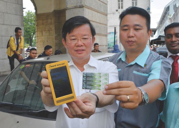 Chow (left) holds the SPG while Ng shows the top-up card yesterday. u00e2u20acu201d Picture by R. Mahgeshannn