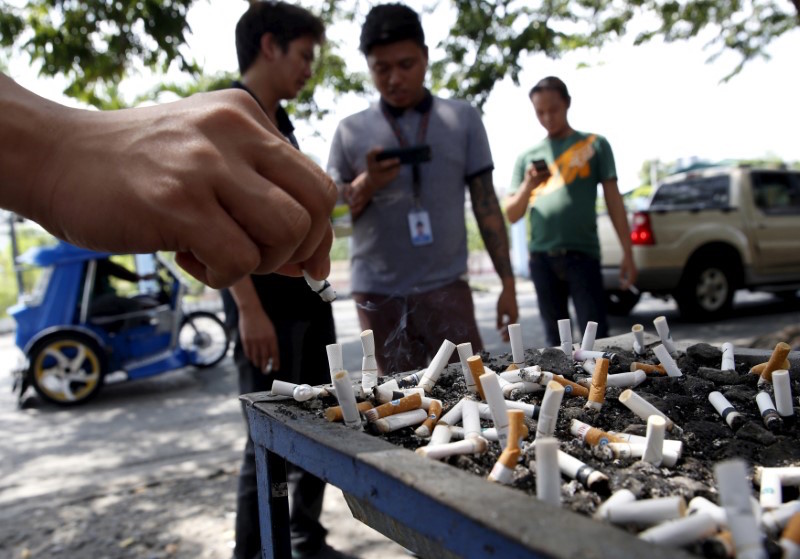 A smoker places a cigarette stub on a tray filled with stubs beside a road in Las Pinas city, Metro Manila Philippines August 7, 2015. u00e2u20acu201d Reuters pic