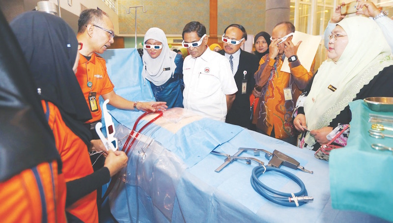 Dr Subramaniam (centre) uses 3-D glasses to view a medical display. u00e2u20acu201d Picture by Razak Ghazali