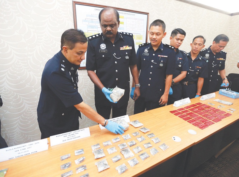 Ravichandran (second from left) and his deputy Supt Abdul Latiff Mehat (left) with the seized drugs on Tuesday. u00e2u20acu201d Picture by Farhan Najib