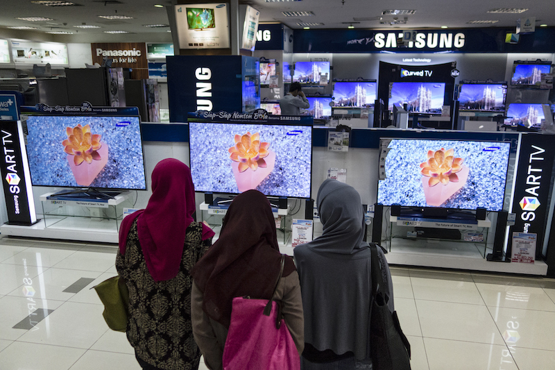 Women look at a display of of large-screen televisions at a shopping mall in Jakarta, Indonesia, July 26, 2014. u00e2u20acu201d NYT pic
