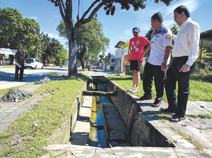 Loh (left) and Wong (centre) show Lee the drain which can be hazardous to motorcyclists during floods. u00e2u20acu201d Picture by Mohamed Basyir 