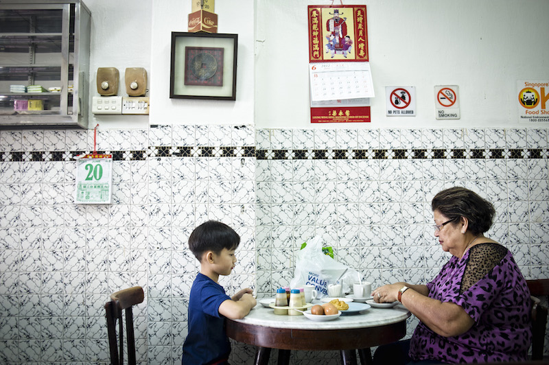 A woman and her grandson have the traditional egg, toast and coffee at the kopitiam Chin Mee Chin Confectionery in Singapore, June 20, 2012. u00e2u20acu201d NYT pic 