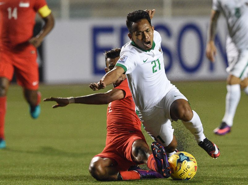 Singapore's Muhanna Shakir Hamzah (back) tackles Andik Vermansah of Indonesia during the Suzuki Cup final round match in Manila November 25, 2016. u00e2u20acu201d AFP pic