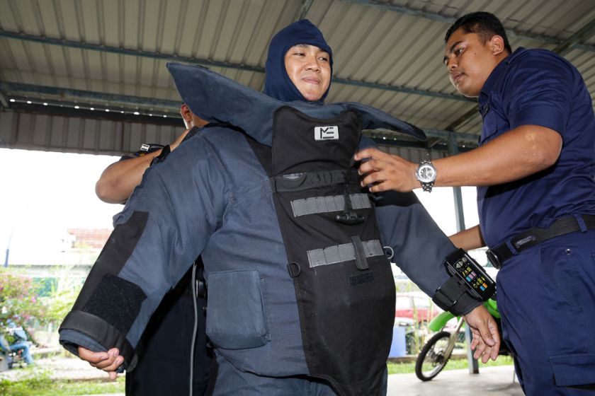 A member of the bomb squad suits up in the 40 kilogramme protective gear. — Picture by Choo Choy May