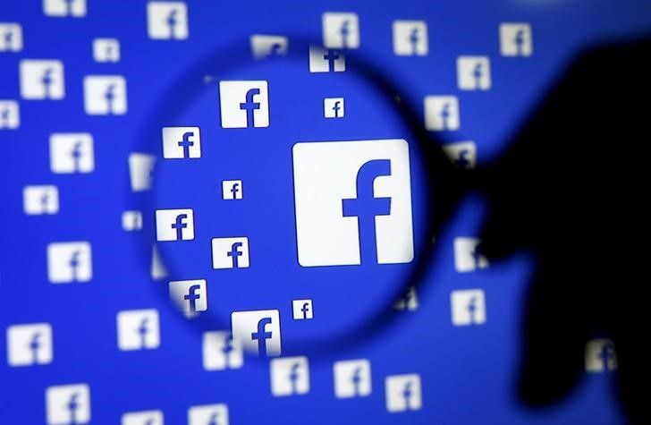 A man poses with a magnifier in front of a Facebook logo on display in this illustration taken in Sarajevo, Bosnia and Herzegovina, December 16, 2015. REUTERS/Dado Ruvic/Illustration/File Photo