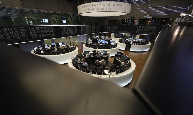 Traders work at their desks in front of the German share price index, DAX board, at the stock exchange in Frankfurt, Germany, October 14, 2016. REUTERS/Kai Pfaffenbach