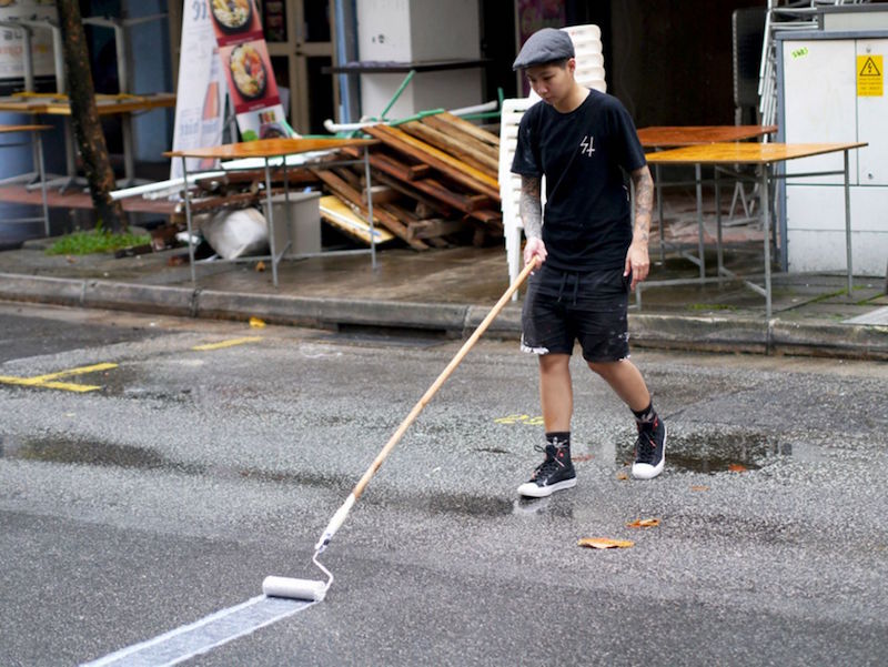 Samantha Lo, otherwise known as the Sticker Lady or SKLO, hard at work for her largest ‘My Grandfather Road’ which was etched in chalk at Circular Road for ‘Circular Spectacular.’ — Picture courtesy of the artist via TODAY