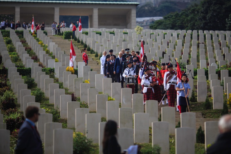 In this photograph taken on December 4, 2016, a pipes and drums band, comprised of members of the Hong Kong Police Force and Royal Canadian Mounted Police, leads a procession past tombstones during the Canadian Commemorative Ceremony honouring those who d