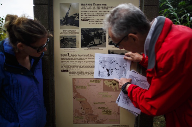 In this photograph taken on December 3, 2016, Martin Heyes (right), a former British Army officer who later served in the Royal Hong Kong Police Force, holds a campaign map showing the defensive Gin Drinkers Line over an information board erected at an anti-aircraft artillery site used during the Battle of Hong Kong as he leads a guided historical walk along the territory’s Wong Nai Chung Gap trail. — AFP pic