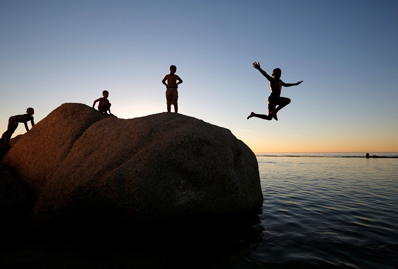 Children leap into a tidal pool as temperatures soar at Camps Bay beach in Cape Town, South Africa.