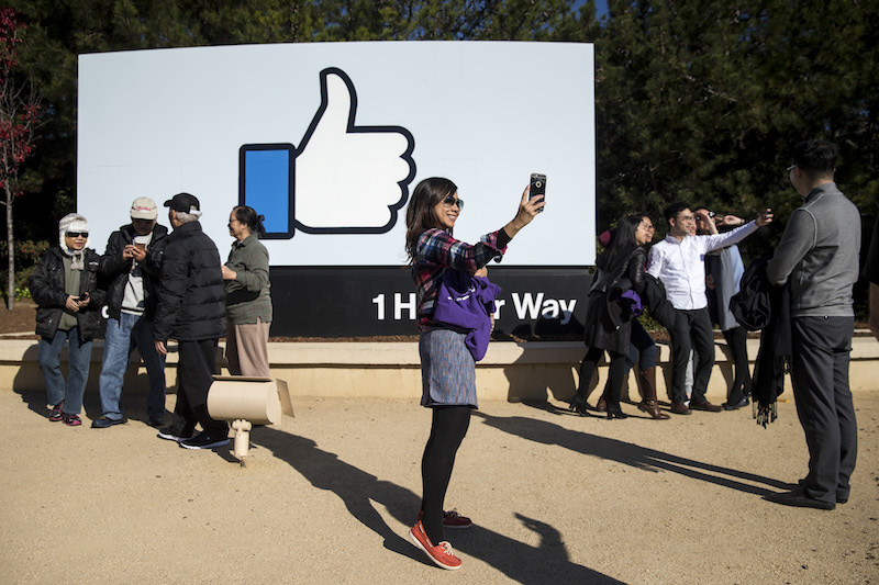 A graduate student from the Chinese University of Hong Kong takes a selfie in front of a Facebook sign at the entrance to the headquarters in Menlo Park, California, December 1, 2016. u00e2u20acu201d Picture by Laura Morton/The New York Times