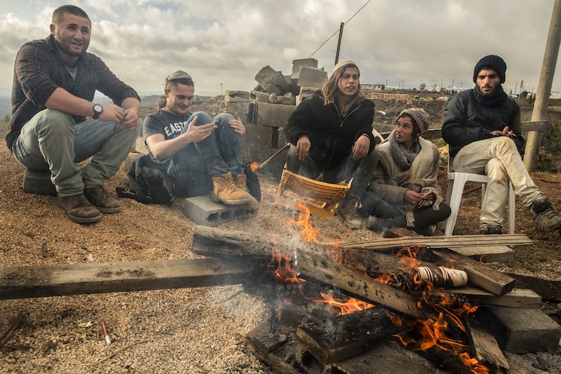 Young Israeli settlers gather around a fire in the settlement outpost of Amona, which was established in 1997 and built on private Palestinian land, in the Israeli-occupied West Bank on December 18, 2016. u00e2u20acu201d AFP pic