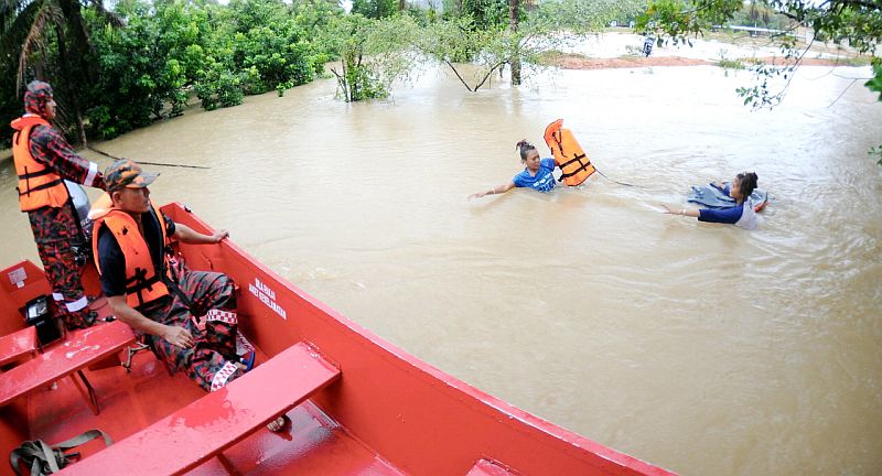A member of the Fire and Rescue Department throws a life jacket to two teenagers attempting to wade to safety in flood waters in Kampung Kolam, December 31, 2016. u00e2u20acu2022 Bernama pic