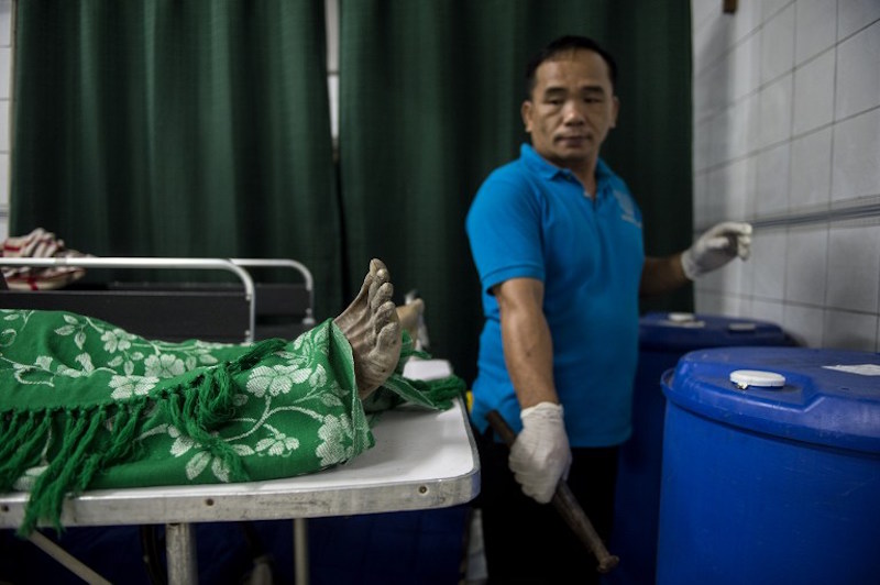 Embalmer Alejandro Ormeneta gets formalin from a drum and prepares embalming instruments before operating on a body in the morgue of the Veronica Memorial Chapel in Manila December 2, 2016. u00e2u20acu201d AFP pic