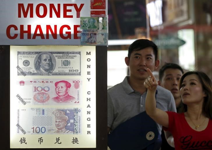 People look at the exchange rate at a moneychanger displaying a poster of US dollar bill, Chinese yuan and the ringgit in Singapore August 24, 2015. u00e2u20acu201dReuters pic