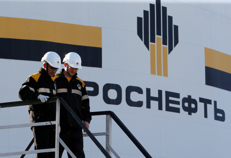 Workers stand next to a logo of Russiau00e2u20acu2122s Rosneft oil company at the central processing facility of the Rosneft-owned Priobskoye oil field outside the West Siberian city of Nefteyugansk August 4, 2016. u00e2u20acu201d Reuters pic