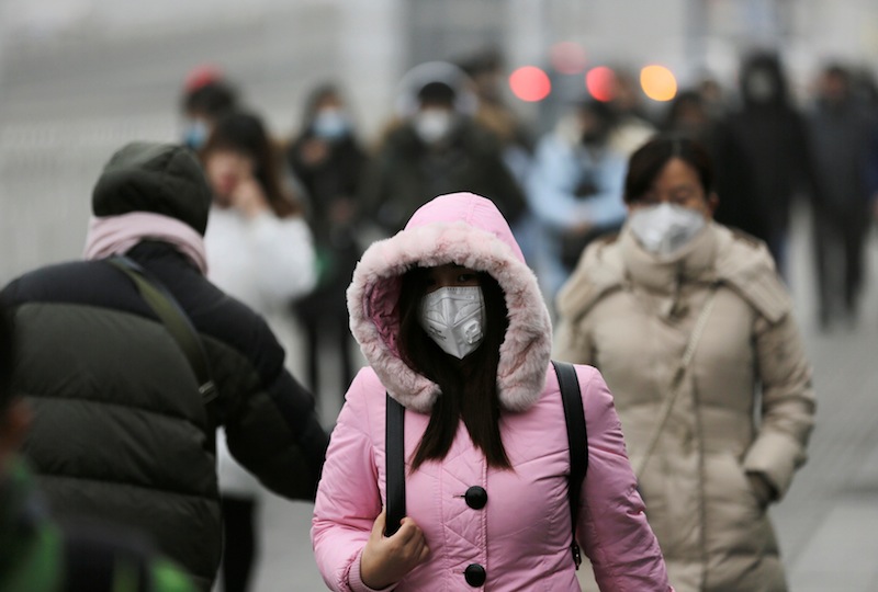 People wearing masks walk toward an office building during the smog after a red alert was issued for heavy air pollution in Beijing's central business district, China, December 21, 2016. u00e2u20acu201d Reuters pic