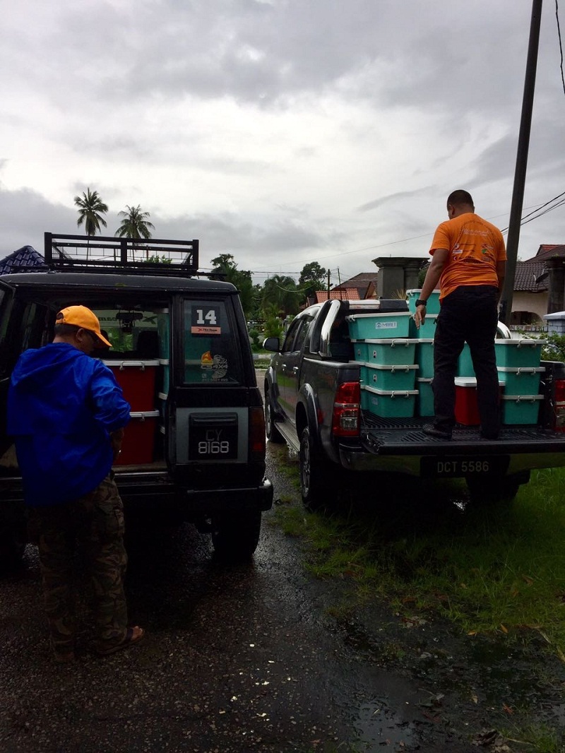 Volunteers working together to unload hygiene kits from a convoy of four-wheel drives provided by the X-tra Team 4x4 & Dirtbikes.