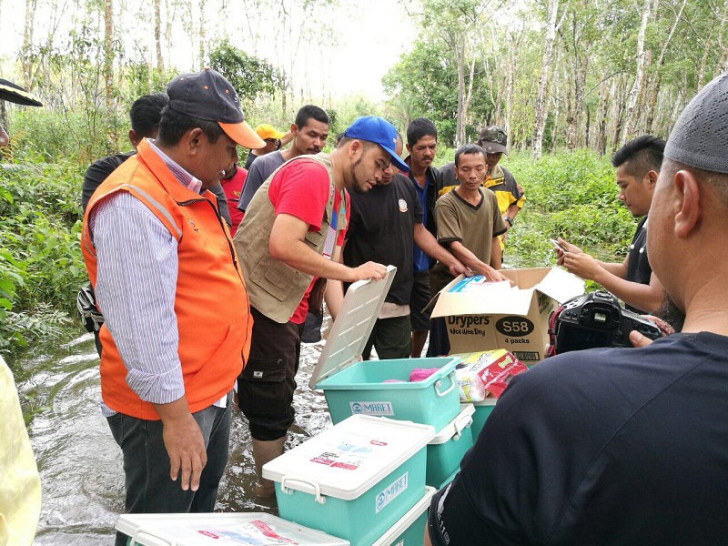 Imaret’s Dr Tuan Zam showing the contents of a hygiene kit to Rantau Panjang flood victims as an orange-vested volunteer from Kelantan’s Social Welfare Department looks on.