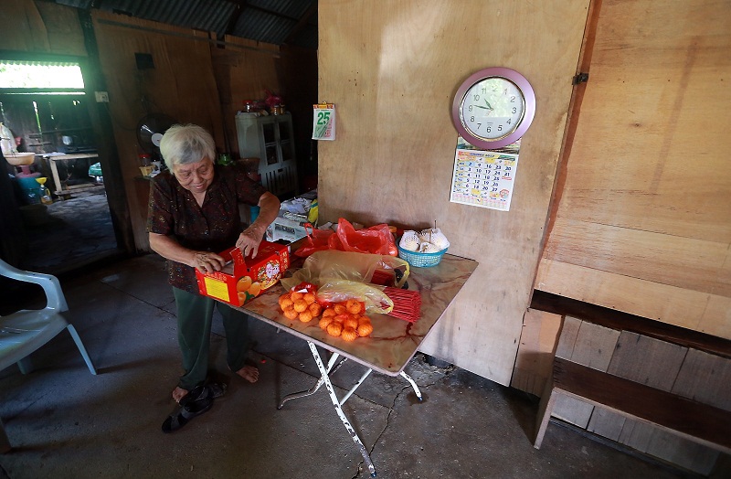 Su arranges the mandarin oranges and prayer items she was able to save from the flood water which hit her house two days ago at in Desa Beruas. u00e2u20acu201d Picture by Farhan Najib