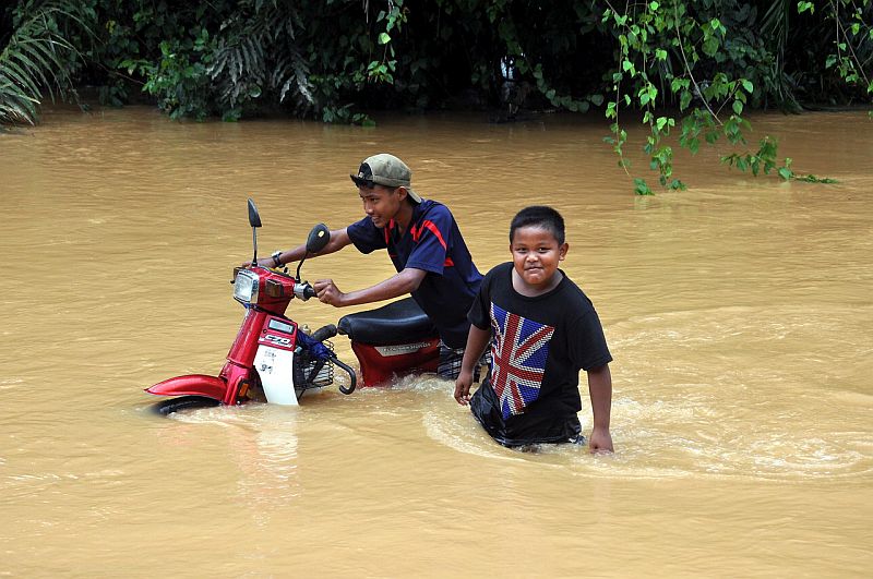 Dua remaja terpaksa menolak motosikal ketika meredah banjir di Kampung Nibong, Hulu Terengganu semalam. u00e2u20acu201d Foto Bernama