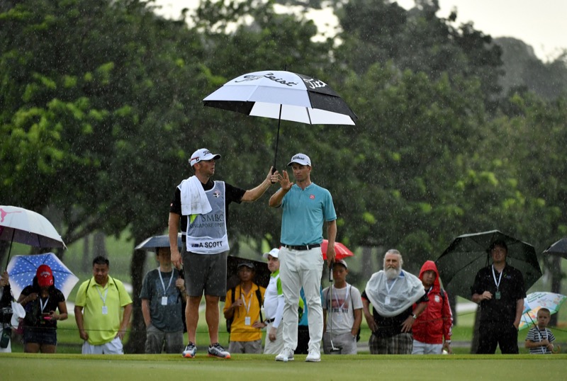 This handout photo provided by Lagardere Sports and taken on January 21, 2017 shows Adam Scott of Australia sheltering from the rain during the third round of the Singapore Open golf tournament taking place in Singapore from January 19 to 22. u00e2u20acu2022 AFP pic