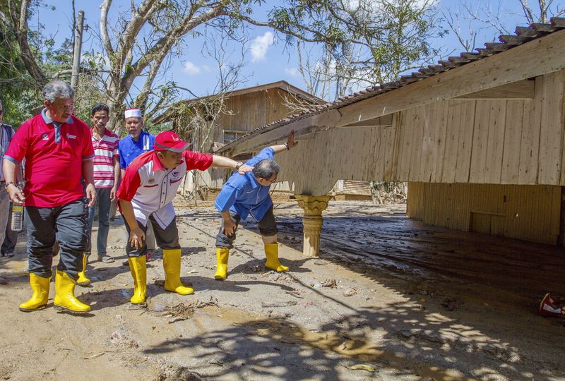 Deputy Minister of Rural and Regional Development Datuk Ahmad Jazlan Yaakub (second right) surveying a house submerged in mud in Kampung Bukit Besi, Machang, January 15, 2017. u00e2u20acu201d Bernama pic