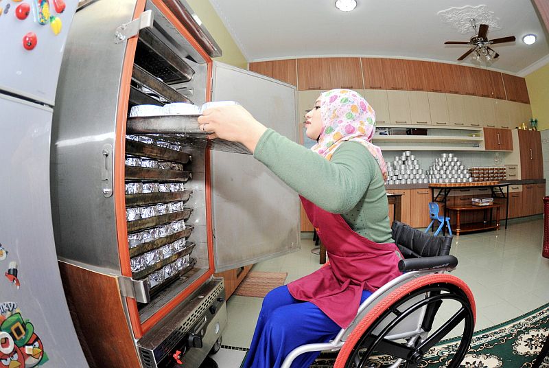 Haziqah Nurul Huda Harun, 20, memasukkan adunan kuih bakul ke dalam tempat pembakaran untuk memenuhi tempahan, termasuk dari Qatar dan Singapura. u00e2u20acu201d Foto Bernama 