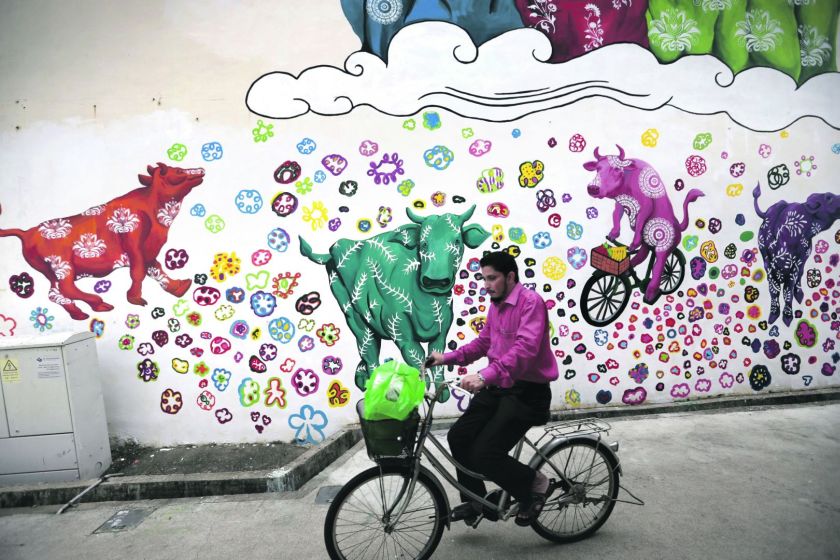 A man cycles past a mural at Little India. — TODAY pic