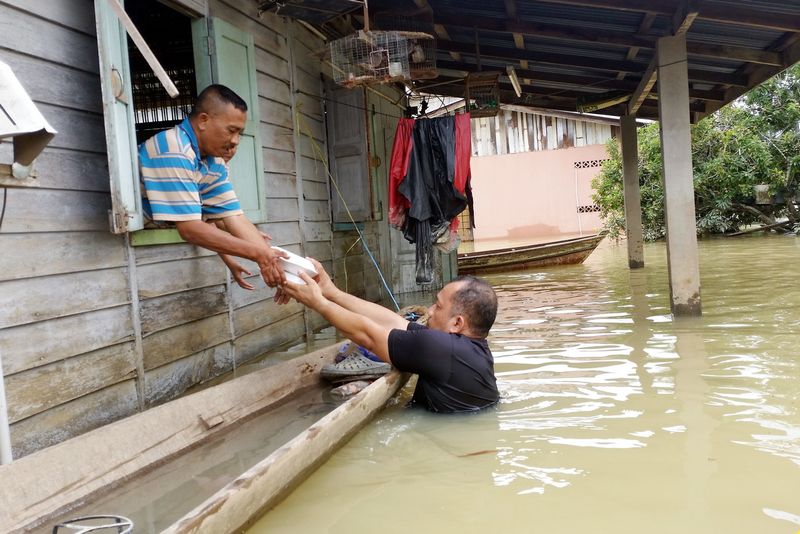 Sukarelawan Amran Abd Rahman, 51, menghulurkan makanan melalui tingkap kepada penduduk yang rumahnya ditenggelami air banjir di di Rantau Panjang, Kelantan. u00e2u20acu201d Foto Bernama