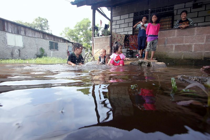 Beberapa kanak-kanak seronok bermain air yang melimpahi jalan masuk ke beberapa rumah penduduk di Kampung Cherating Baru, Kuantan 1 Januari 2017. u00e2u20acu201d Foto Bernama