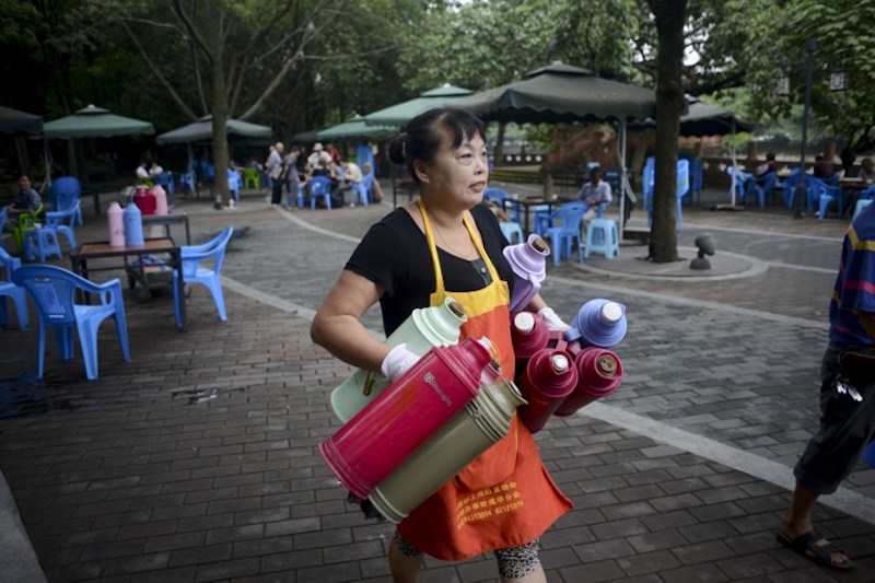 A waitress holds thermos bottles at an outdoor teahouse at a park in Chengdu, southwest China’s Sichuan province, September 8, 2016. — AFP pic