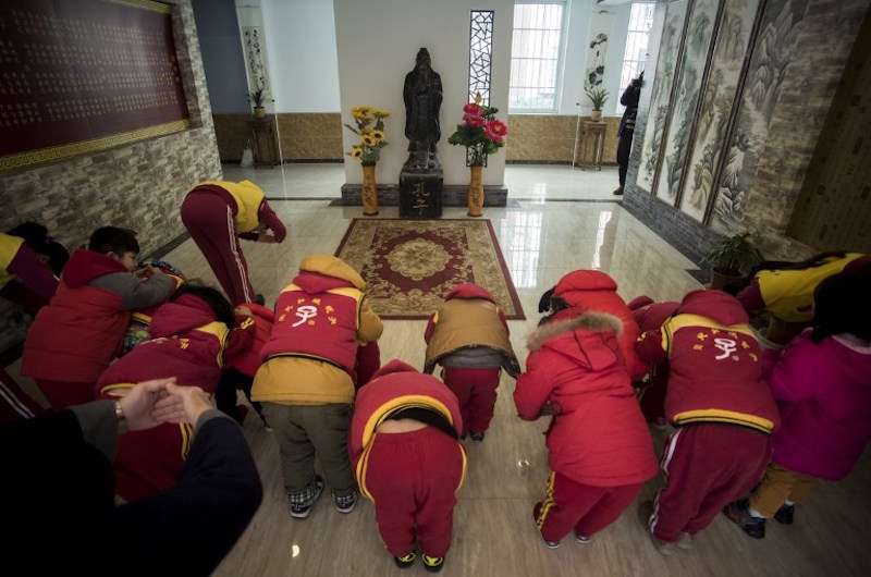 Children bow before a statue of Confucius after a class at a Confucius kindergarten in Wuhan February 2, 2016. — AFP pic