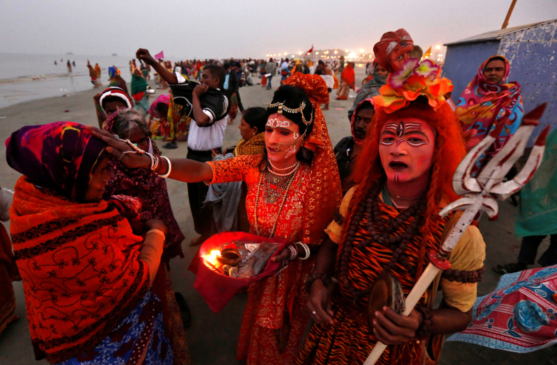 Two Indian men dressed as Hindu Lord Shiva (right) and Goddess Parvati (centre) give blessings to a pilgrim at the confluence of the river Ganges and the Bay of Bengal, ahead of the u00e2u20acu02dcMakar Sankrantiu00e2u20acu2122 festival at Sagar island January 13, 2017. u00e2u20acu201d Reut
