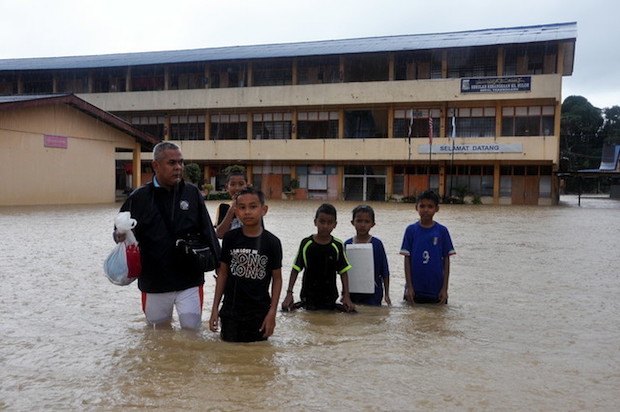 A teacher and his pupils stand in floodwaters that have inundated Sekolah Kebangsaan Kampung Buloh in Permaisuri, Setiu, January 22, 2017. u00e2u20acu201d Bernama pic
