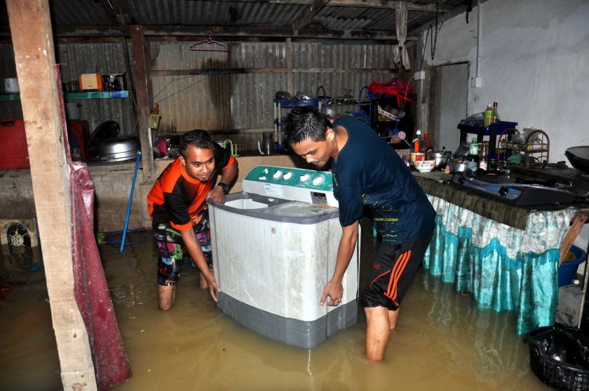 Mohd Helmi Mohd Nawi, 26, dibantu Shamsul Mohammad, 27, mengangkat mesin basuh setelah rumahnya di Kampung Paya Besar, Hulu Terengganu dilanda banjir pada 3 Januari 2017. u00e2u20acu201d Foto Bernama 
