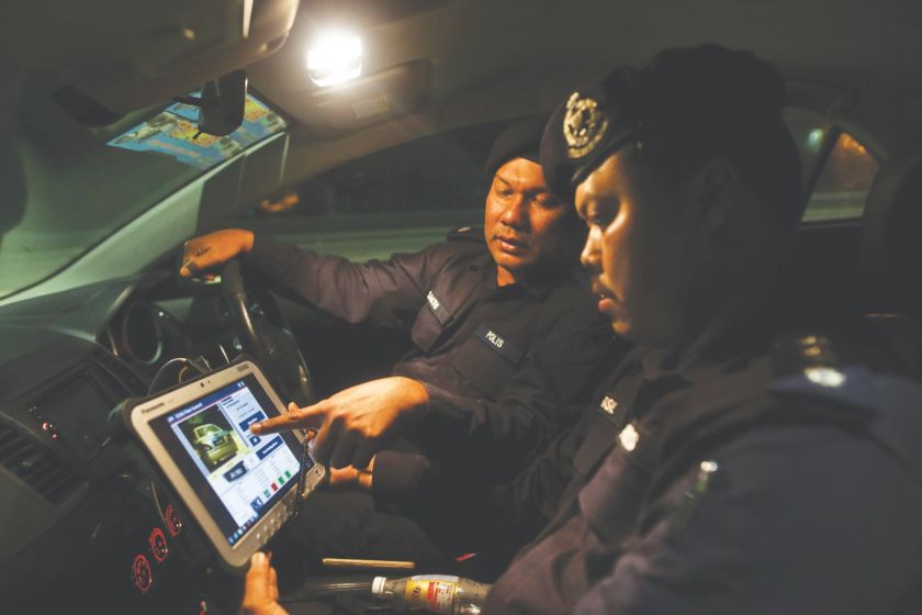 Bakri (left) and ASP Ahmad Al Faisal Abd Ghani check the status of a car using iCOP. u00e2u20acu201d Malay Mail pic
