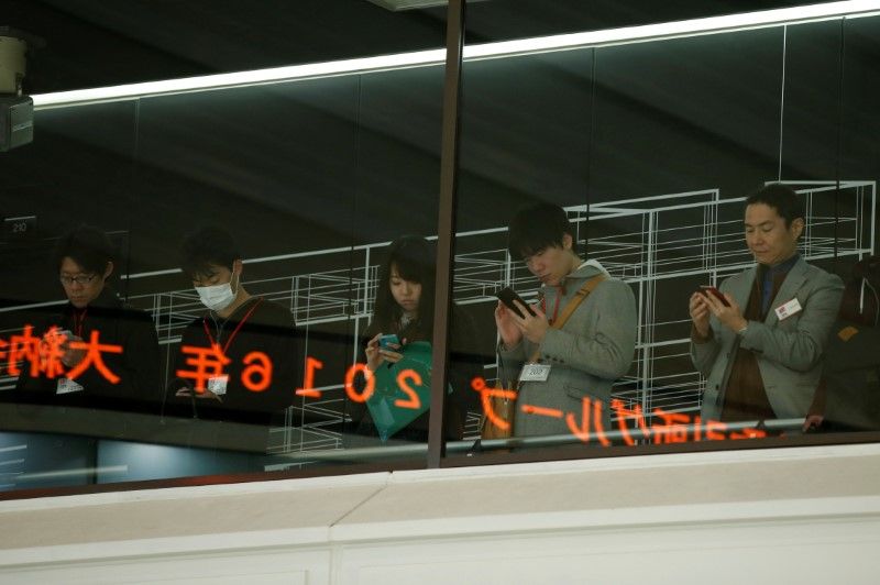 Visitors use their mobile phones before a ceremony marking the end of trading in 2016 at the Tokyo Stock Exchange December 30, 2016. u00e2u20acu201d Reuters pic